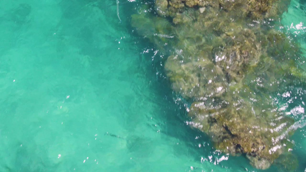 Clear turquoise water over a large submerged rock formation.