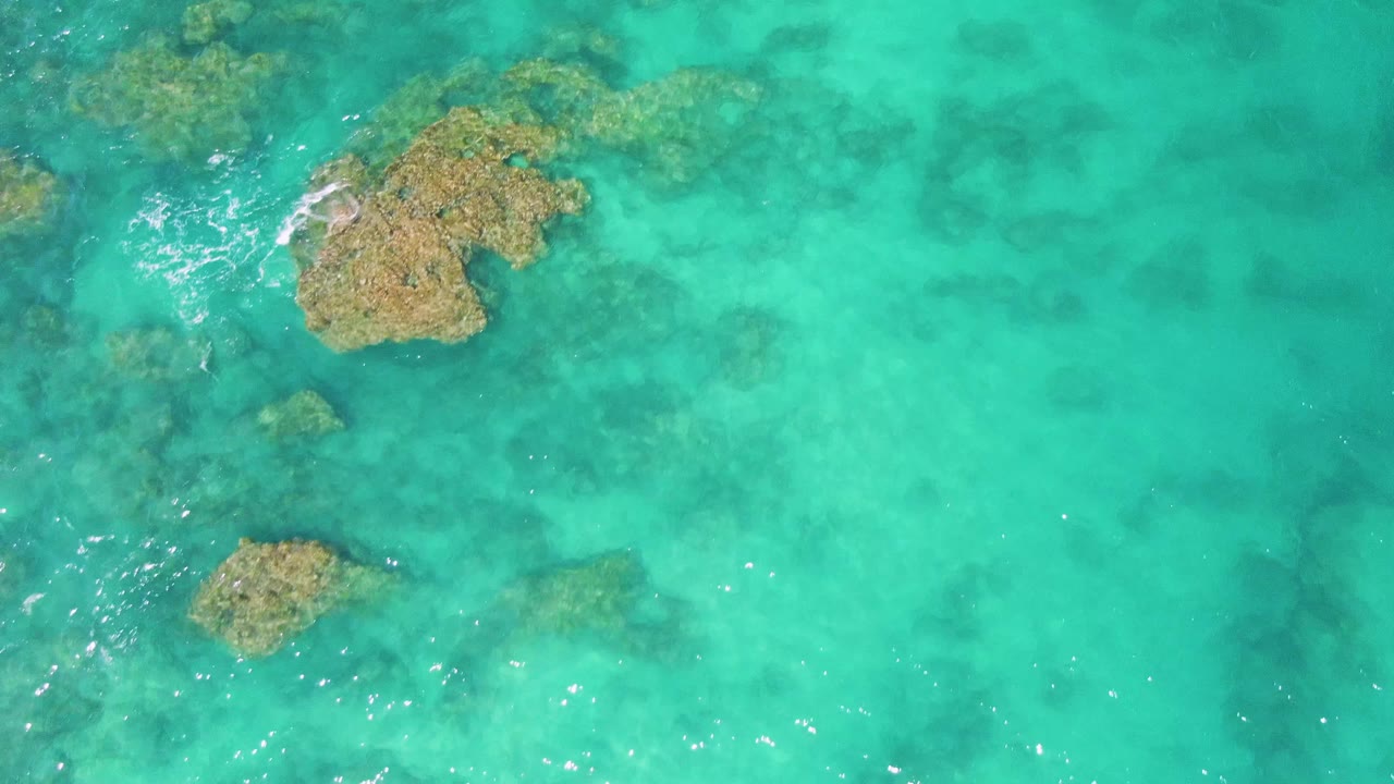 Submerged rock patch in turquoise water with light wave texture.