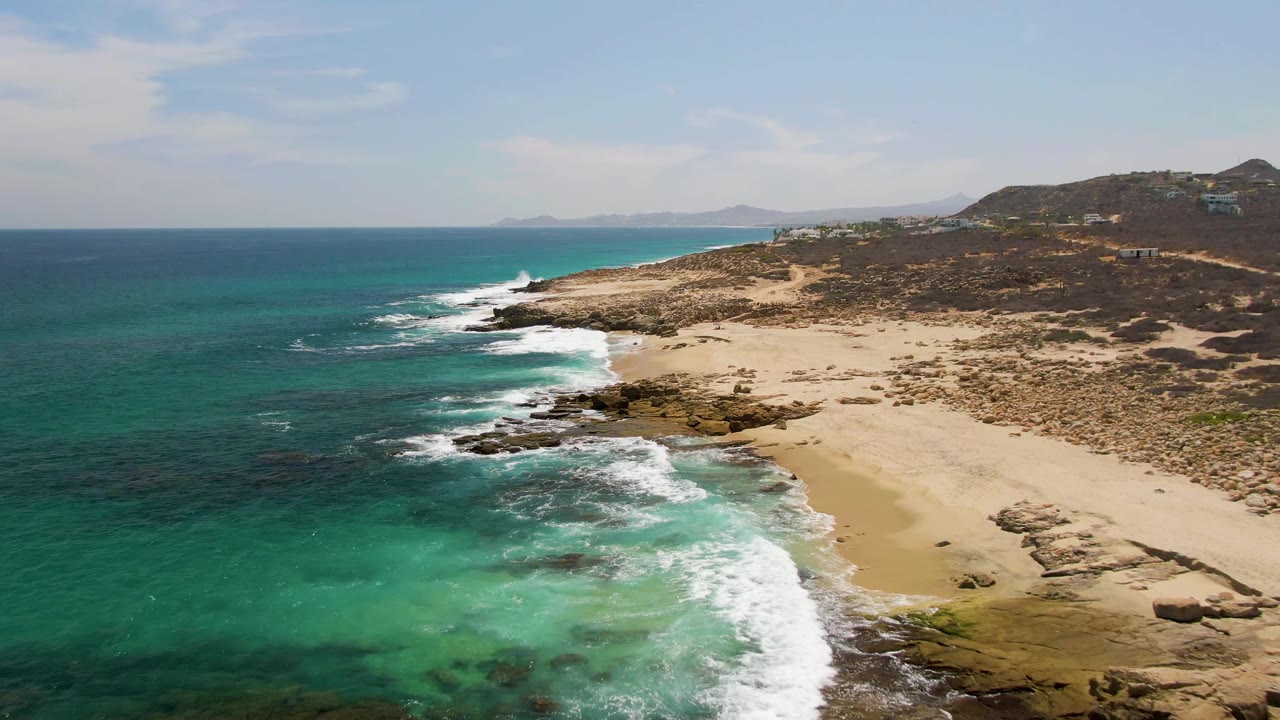 Fourth frame from the clip shows more open blue water to the left, turquoise surf in the lower foreground, the Buzzards Beach sand and rocks to the right, and no visible people.