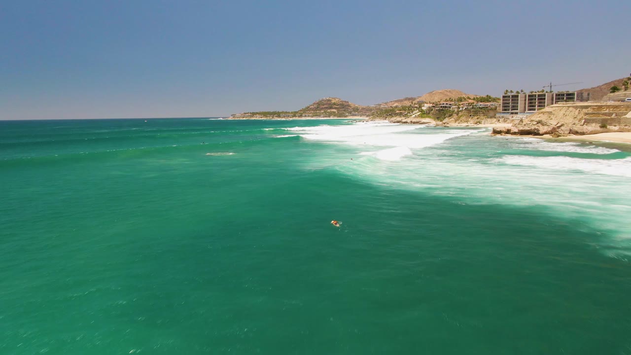 Small swimmer in turquoise water near breaking coastal waves