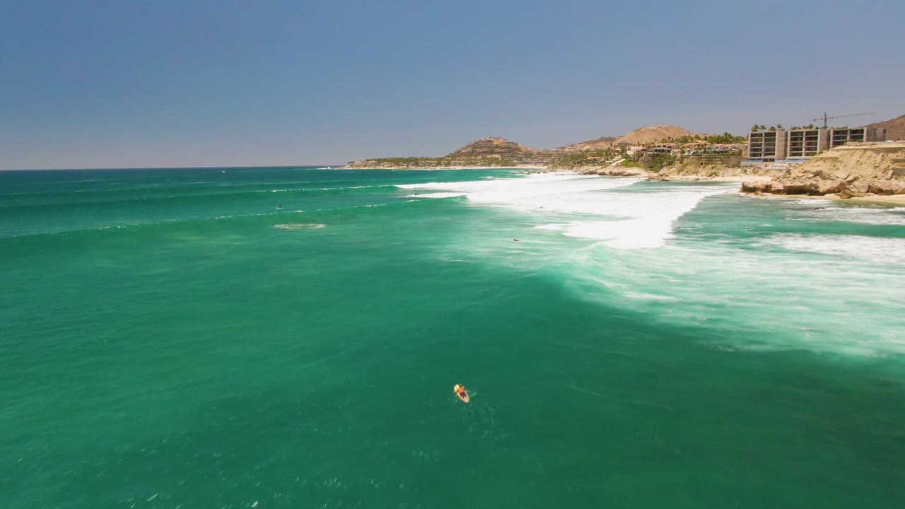 Foamy surf line and swimmer below a rocky coastline