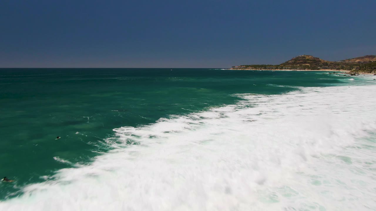 Aerial surf foam covering the right side of a turquoise ocean frame
