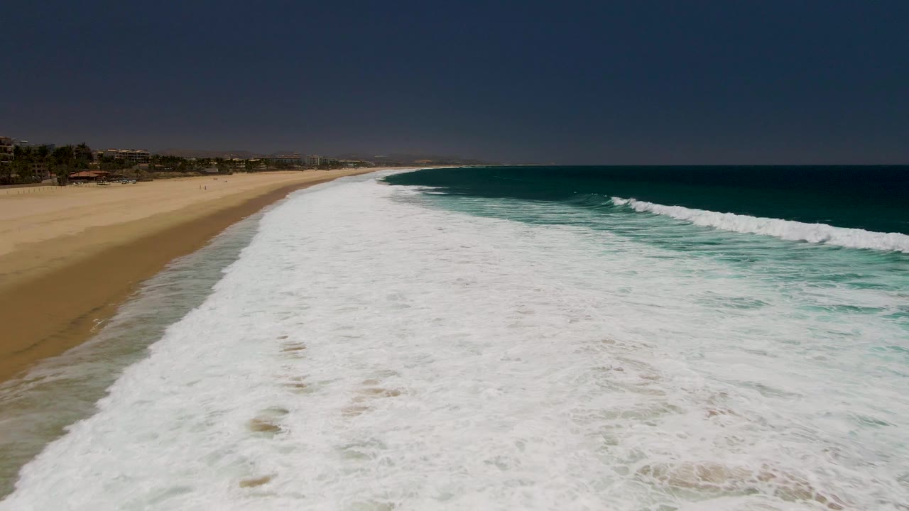 Breaking wave line running parallel to a sandy beach
