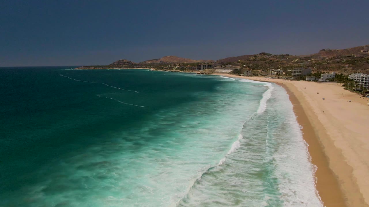 Wide aerial coastline with dark blue water and breaking waves