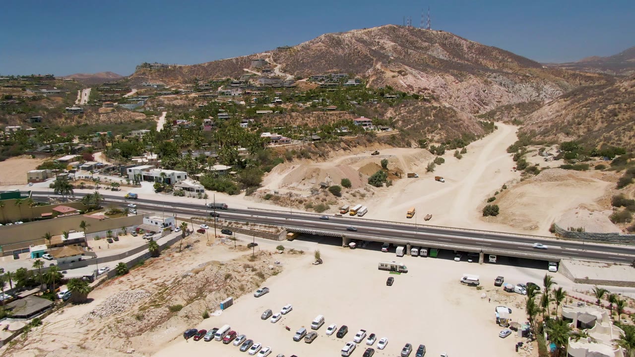 Highway, sandy lot, and mountain ridge seen from above