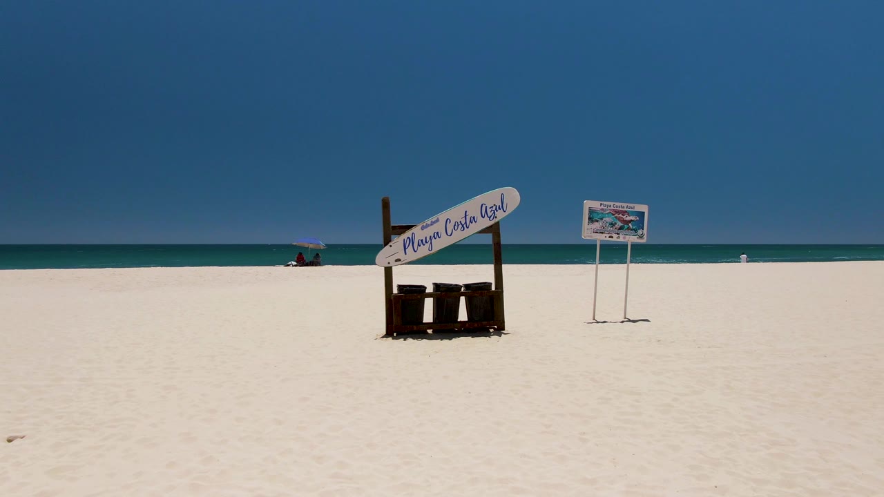 Beach signs on white sand with calm ocean behind