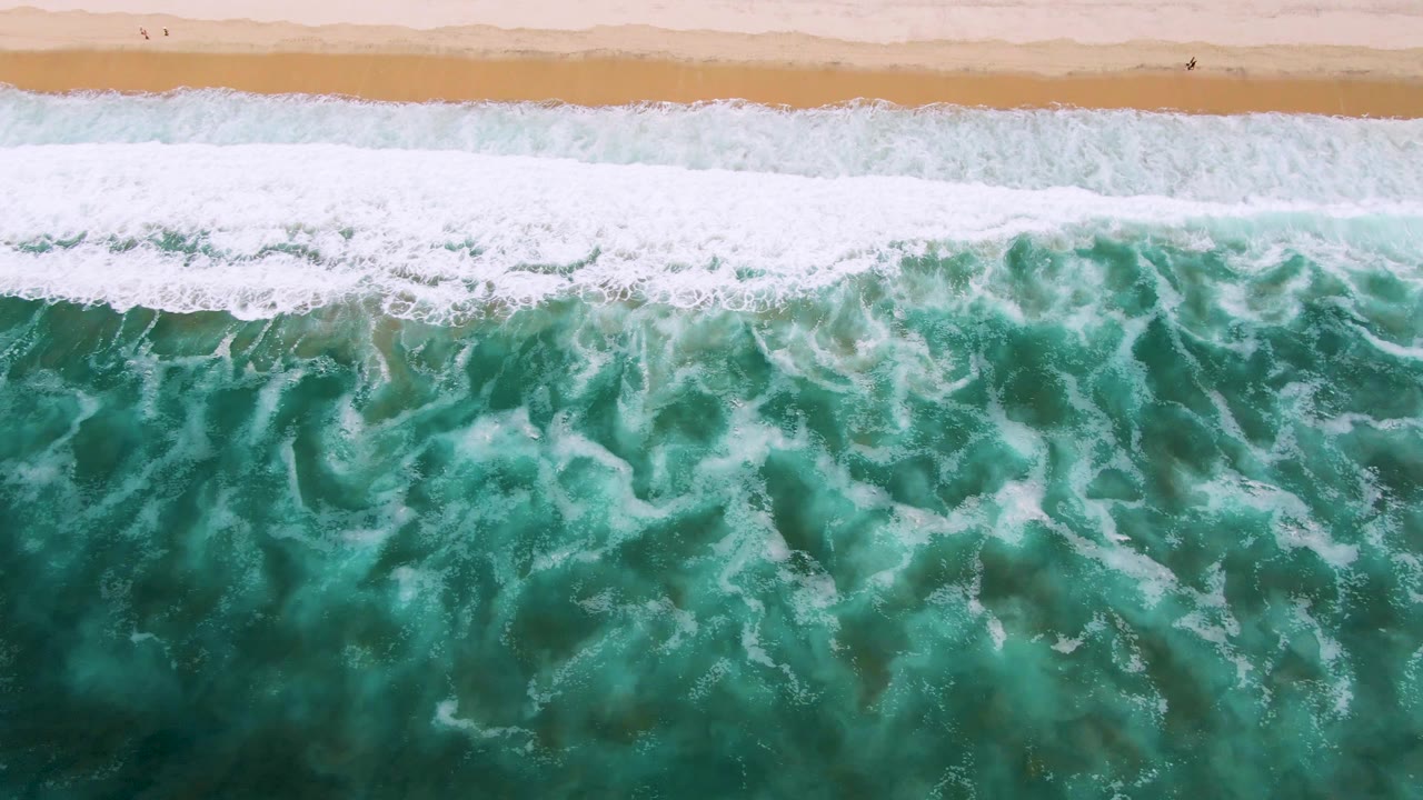 Breaking wave foam below a narrow sandy shoreline