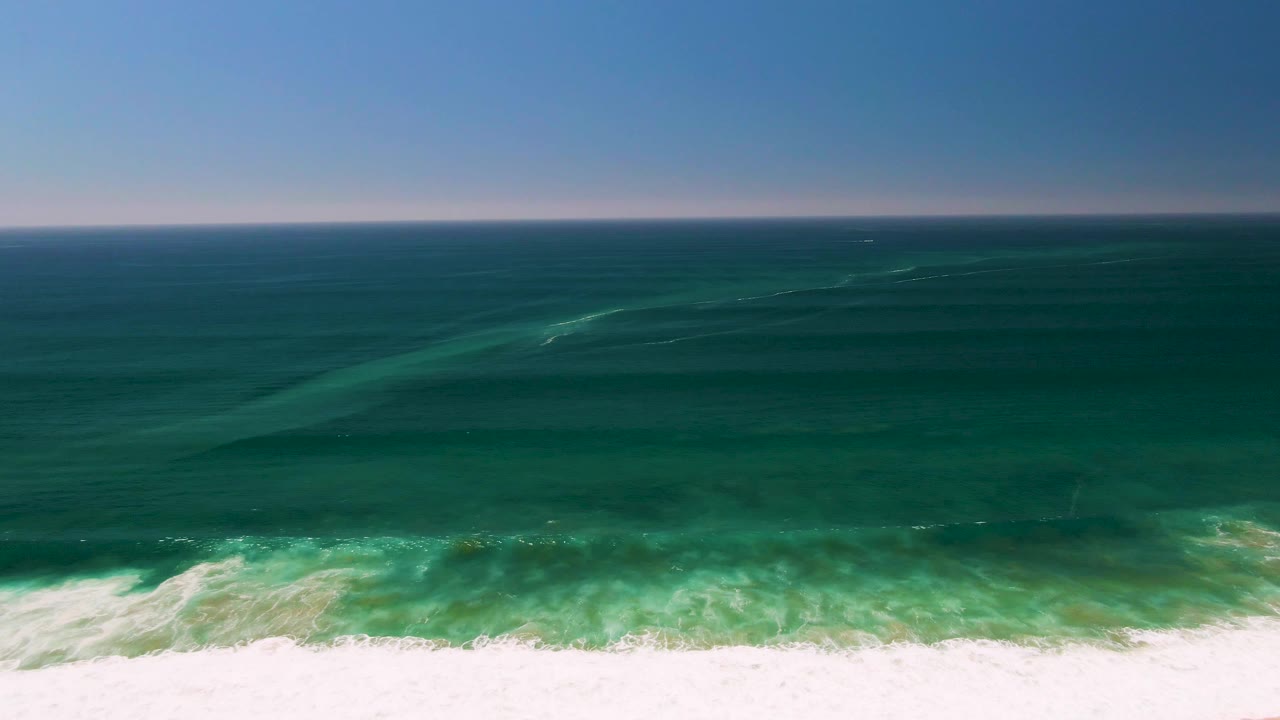 Aerial view of blue-green ocean waves breaking near shore