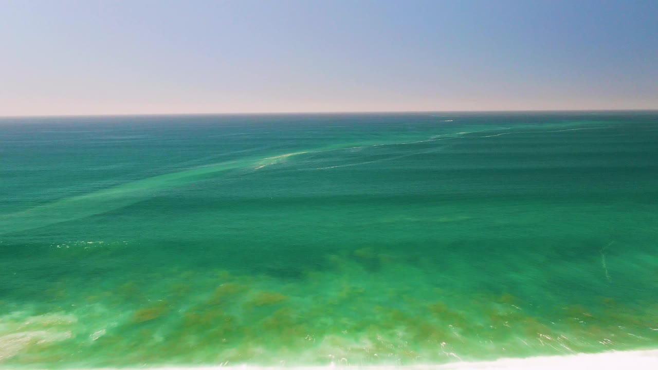 Opening frame of turquoise ocean water in San Jose del Cabo with darker shallow seabed patches beneath the surface and no visible people.
