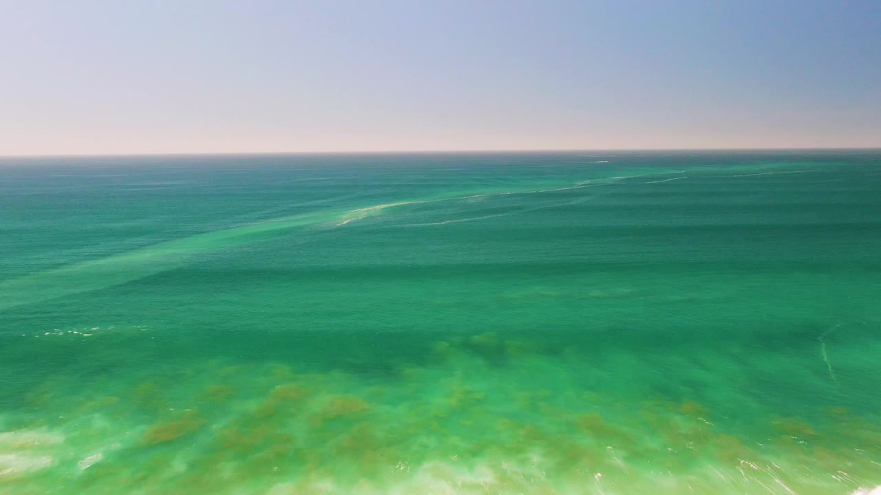 Second frame of San Jose del Cabo ocean water, with a broad green-blue surface, faint ripples, and submerged vegetation-like patches visible below, with no visible people.