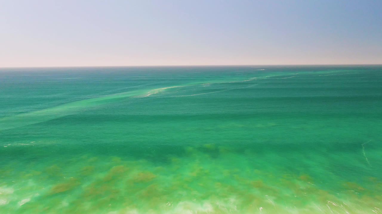 Mid-clip frame showing calm turquoise water off San Jose del Cabo, a faint horizon near the top, and green seabed tones below the surface, with no visible people.