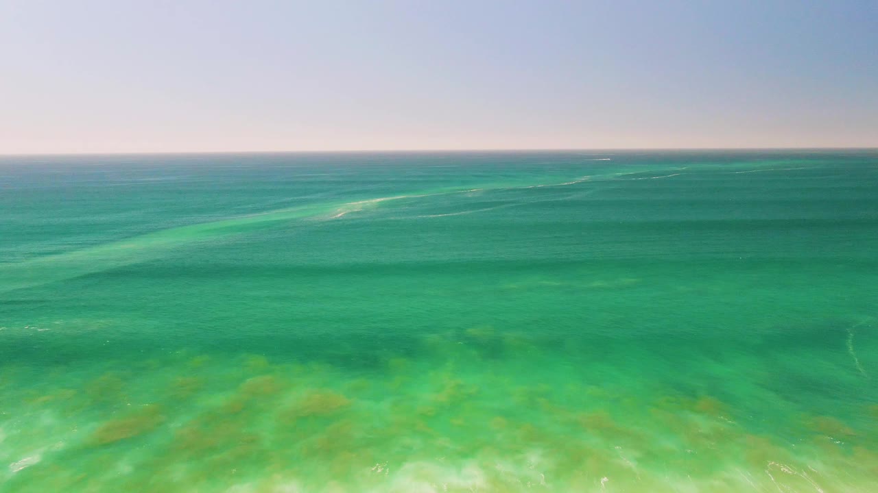 Wide band of turquoise ocean with visible underwater patches.