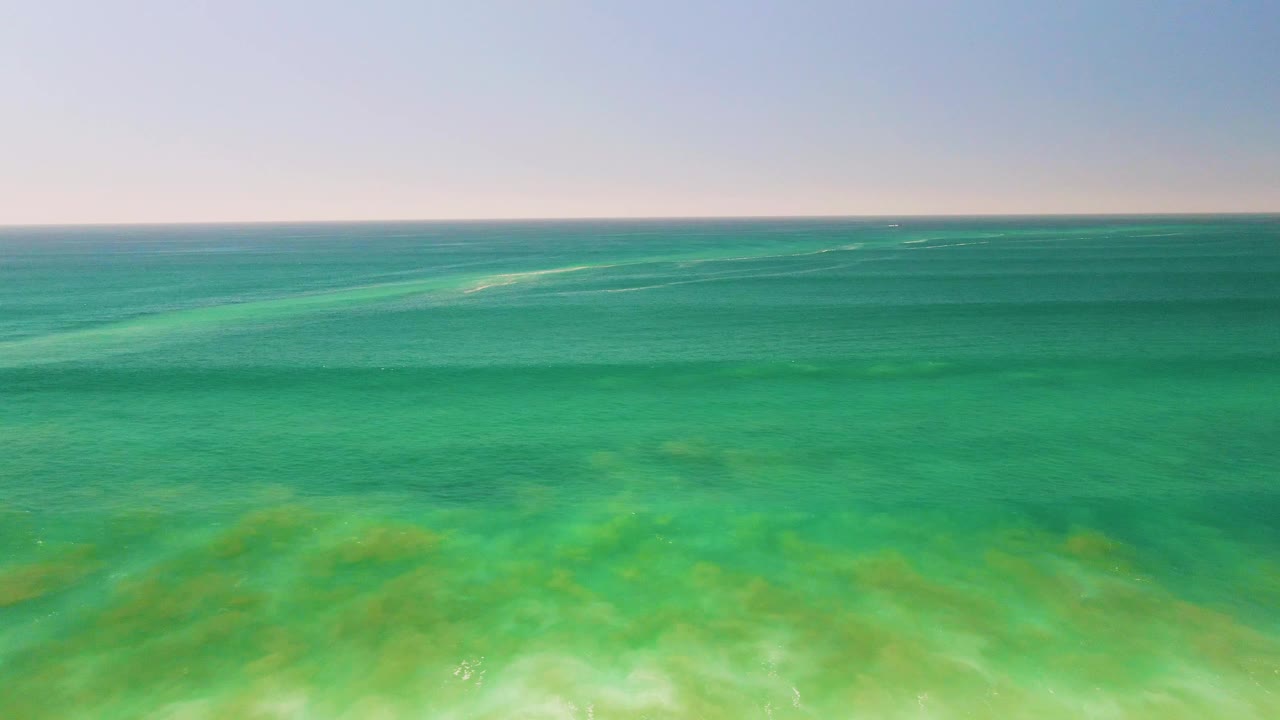 Clear green-blue ocean water in San Jose del Cabo shows pale seabed shapes beneath the surface, with subtle ripples and no visible people.
