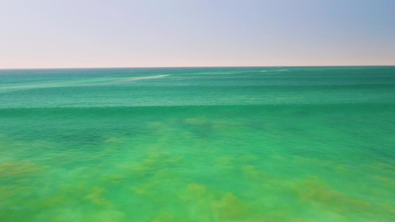 A second view over San Jose del Cabo shallow ocean water shows green-blue surface color, soft wave texture across the middle distance, and no visible people.