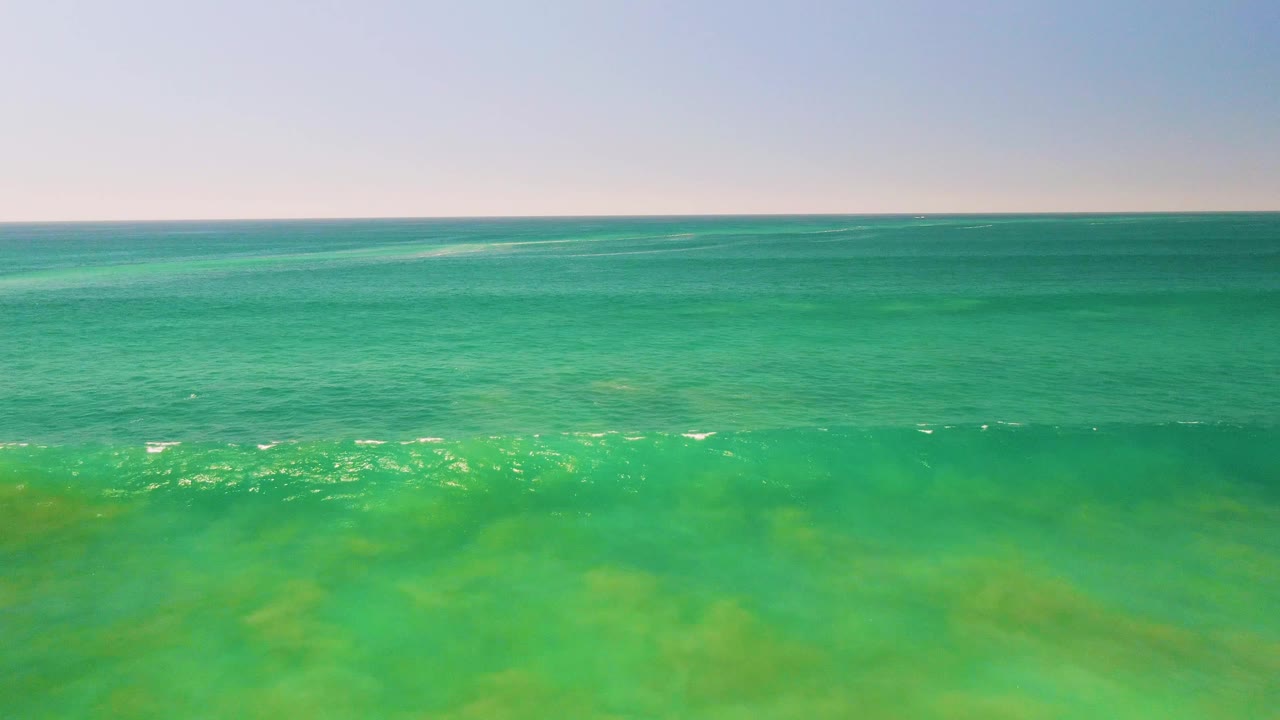 Turquoise ocean surface with breaking foam near the foreground.