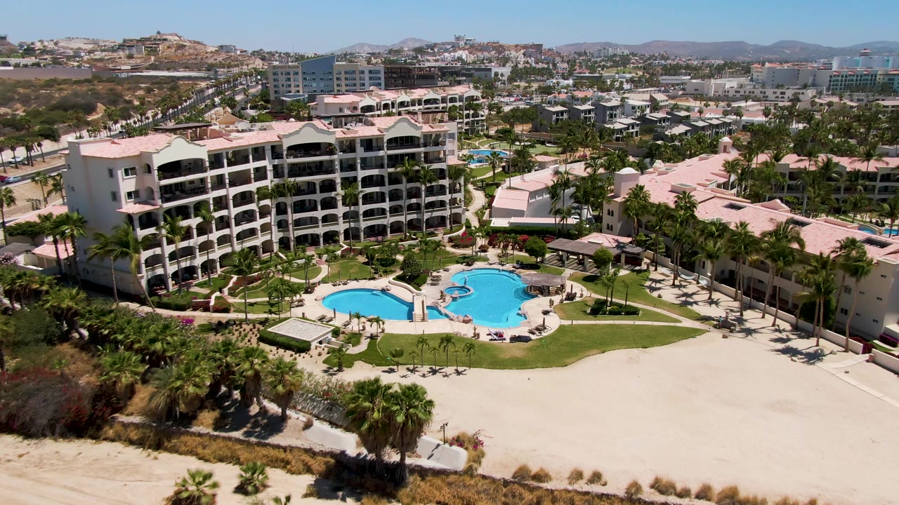 Elevated resort view with pool, palms, beach, and surrounding town.