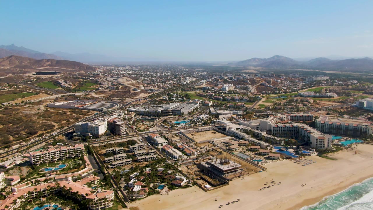 Aerial view of beach resort development, highway, and mountains