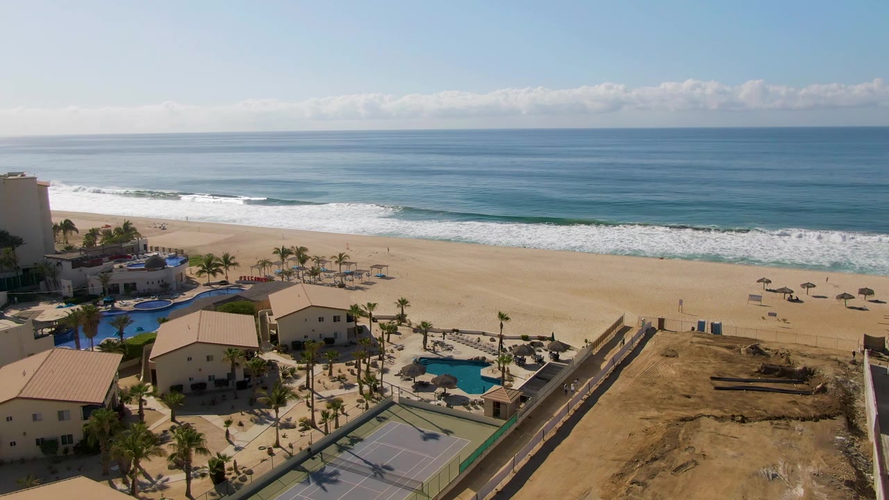 Sunny beach aerial with resort pools and tennis court