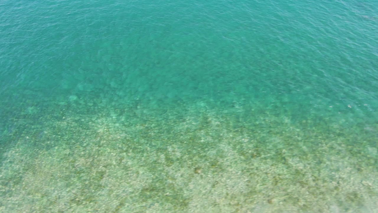 Bright turquoise water ripples over a lightly colored sandy seabed at El Tule Beach in Los Cabos, keeping the frame free of people and shoreline.