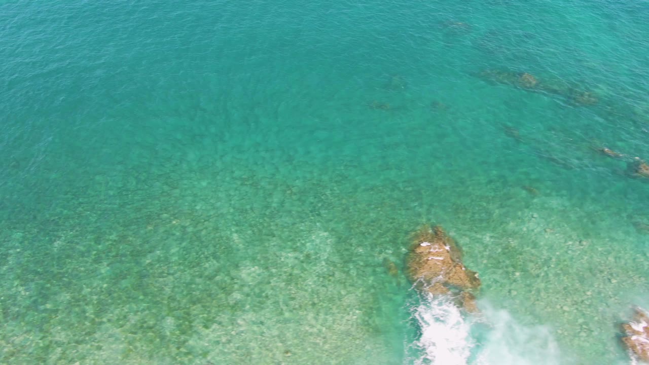 Overhead coastal water with rocks and foam entering from the bottom.