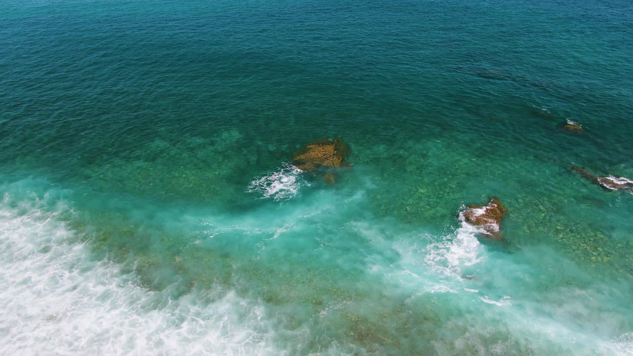 Wave wash receding around shallow ocean rocks