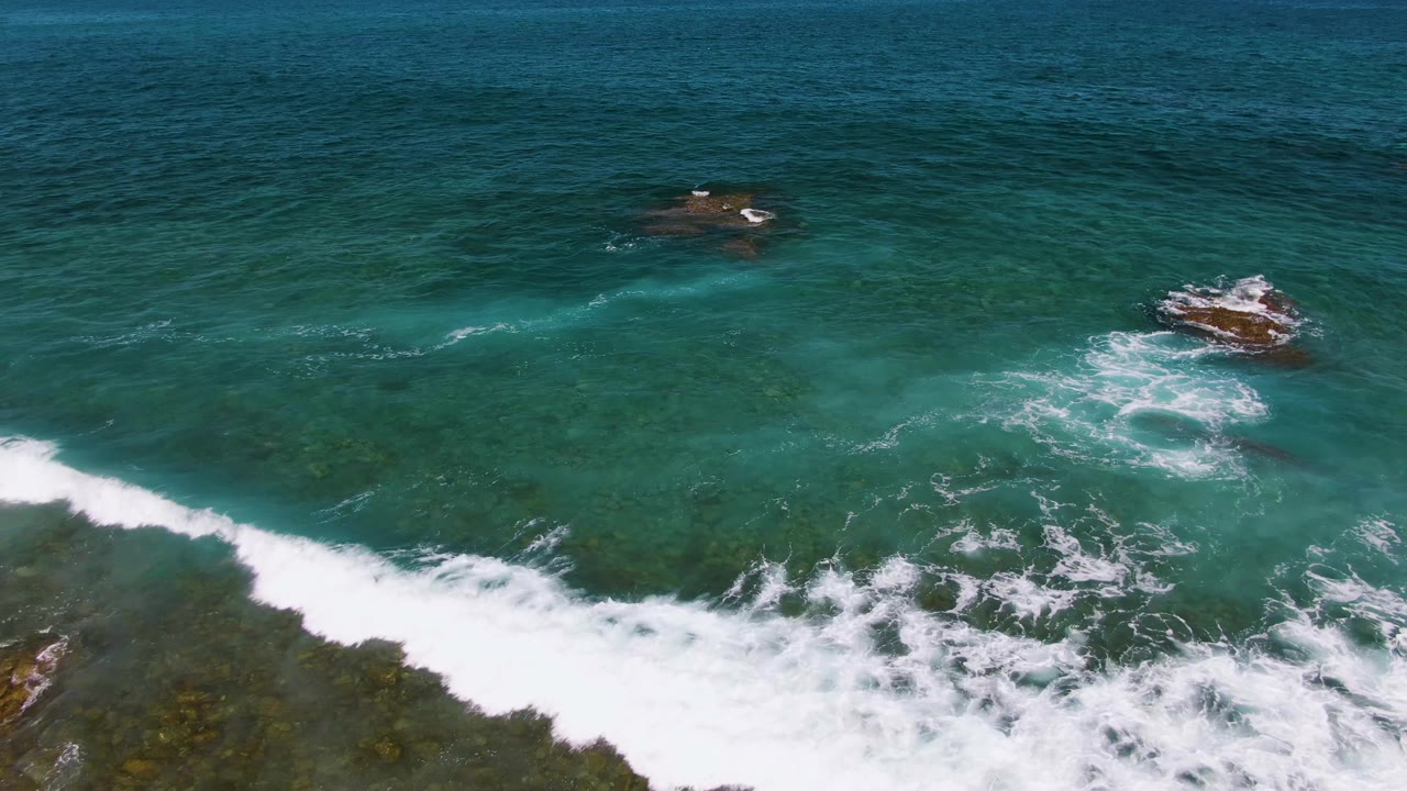 Rocky ocean outcrops sit beyond a large band of breaking surf.