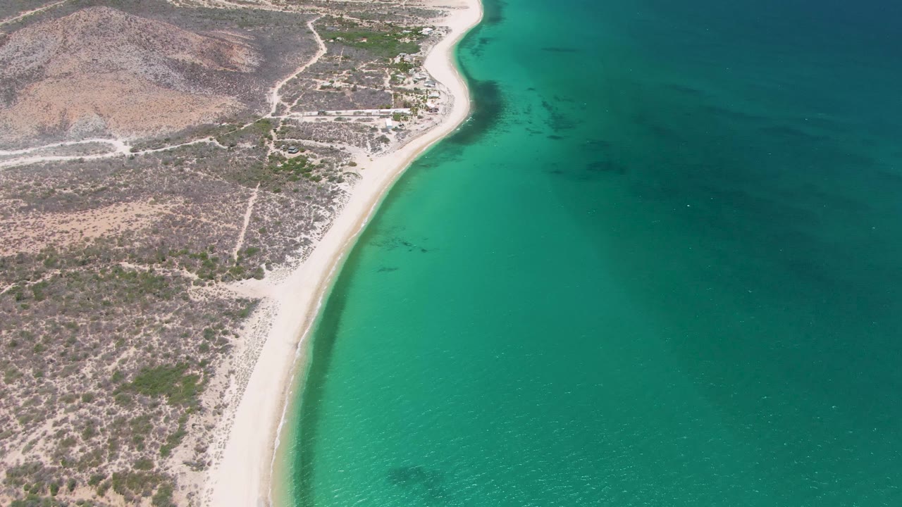 Aerial view of a sandy beach between arid land and turquoise ocean