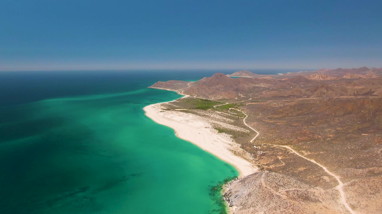 Aerial view of a sandy Mexican coastline with turquoise water and dry inland hills.