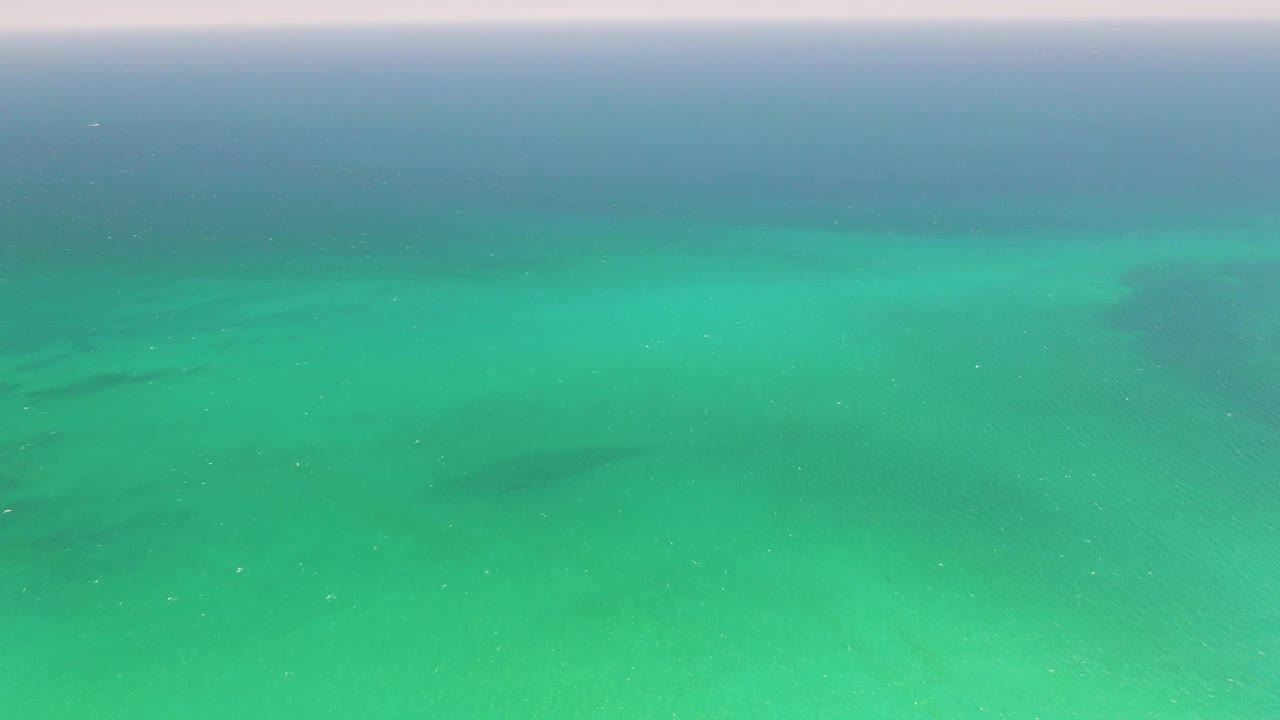 Turquoise ocean water with darker seabed patches and a faint horizon band.