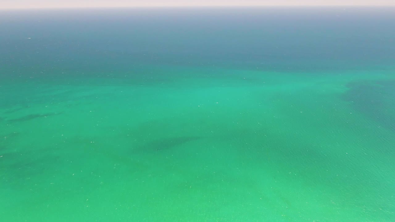 Second frame over Playa Miramar Los Cabos water, showing faint ripples across bright turquoise sea and darker underwater patches, with no visible people.