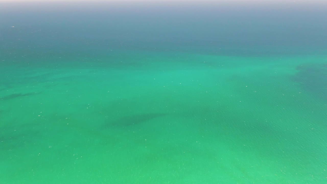 Later frame of Playa Miramar Los Cabos water where the turquoise surface remains open and empty, with faint current lines and darker seabed patches, no visible people.