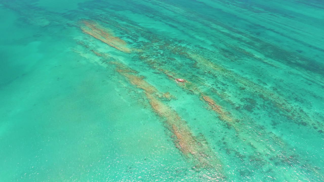 Turquoise shallow water over diagonal coral formations.