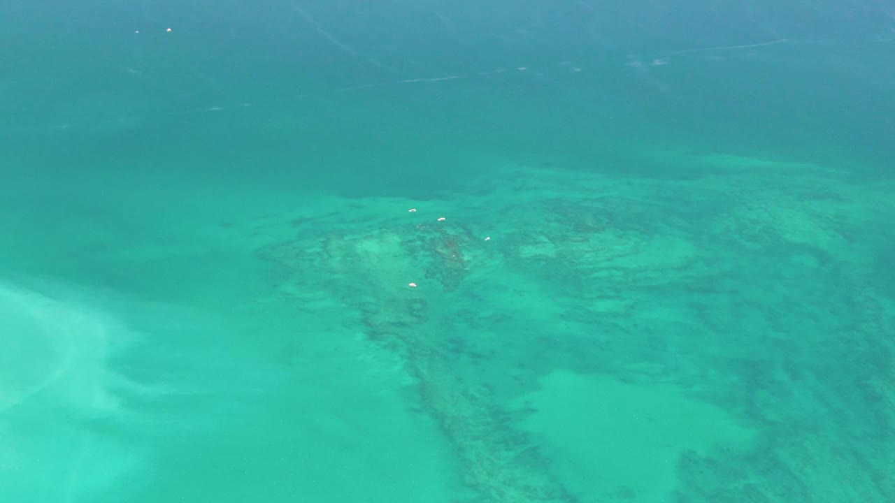 Clear blue-green water with submerged sand and rock texture.