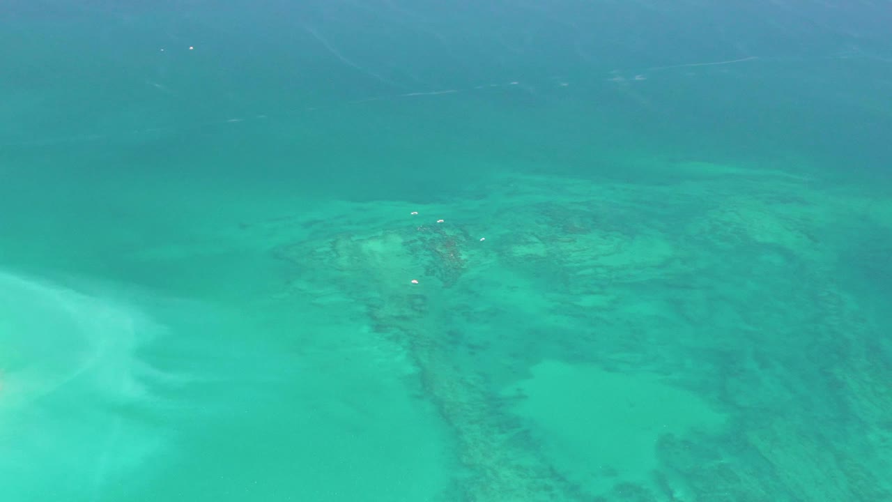The Cabo Pulmo shallows show a pale sand channel cutting through darker underwater texture, with no visible people in the frame.
