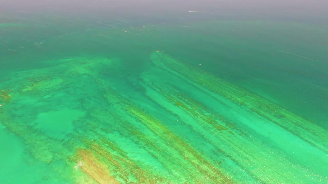 Aerial view of reef streaks under clear turquoise water.