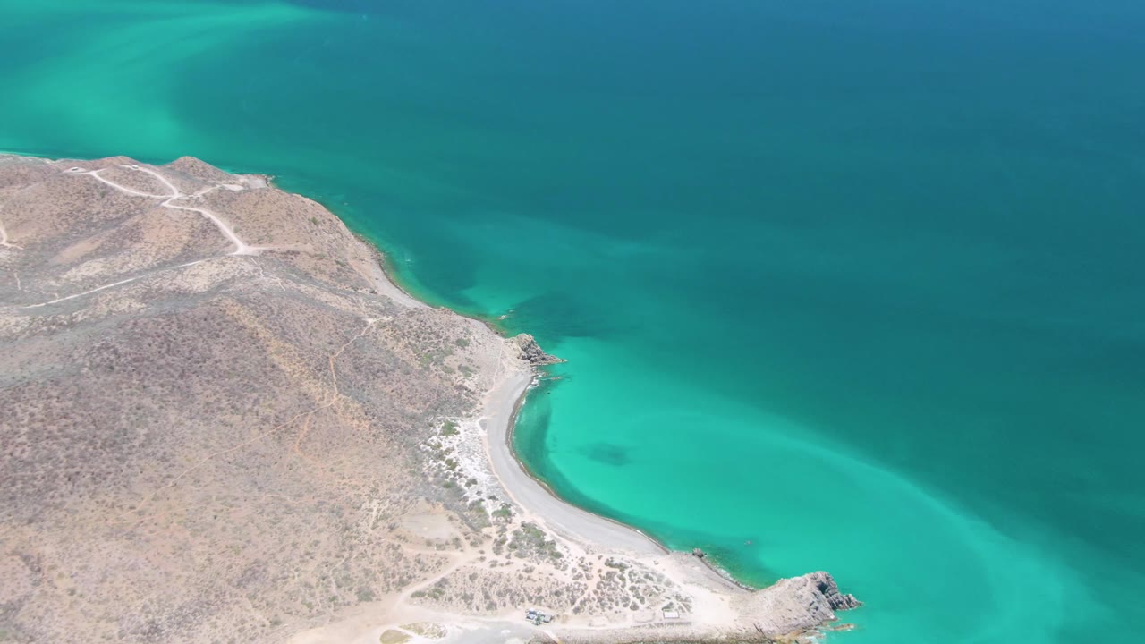 Drone view of dry headland and curved turquoise bay