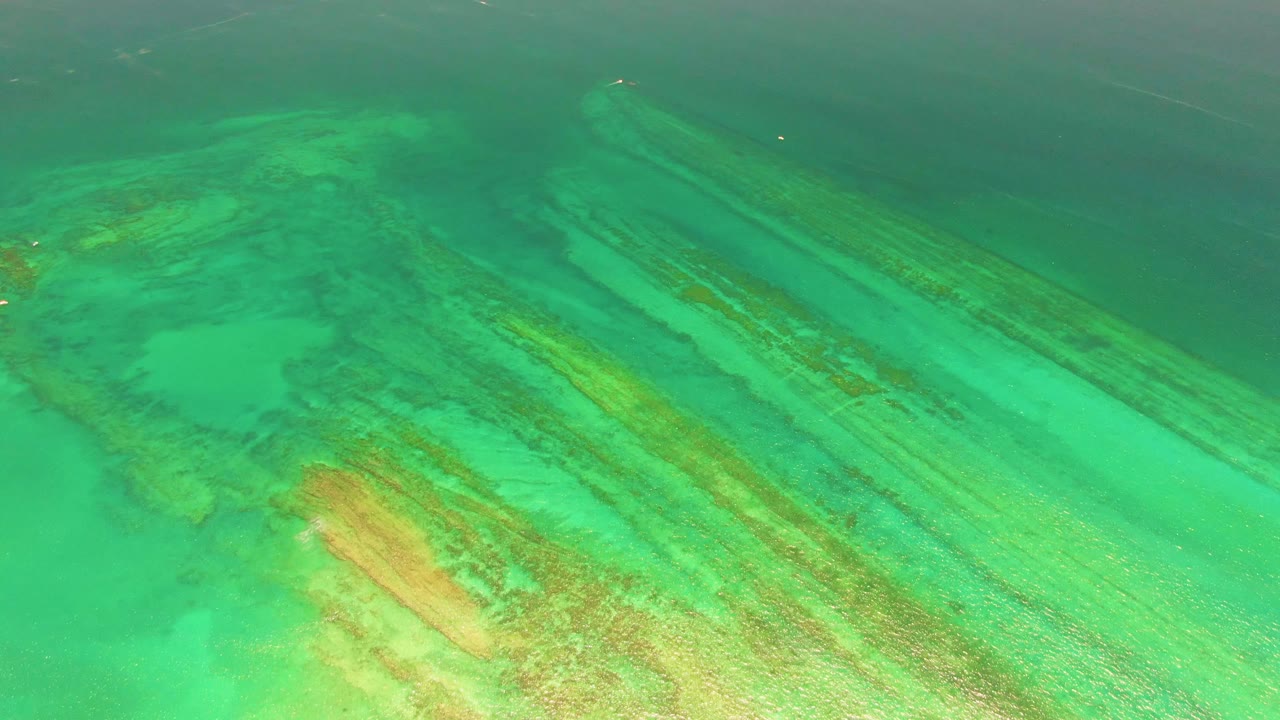 A bright turquoise section of Cabo Pulmo water reveals coral reef formations and pale underwater patches, with no visible people.