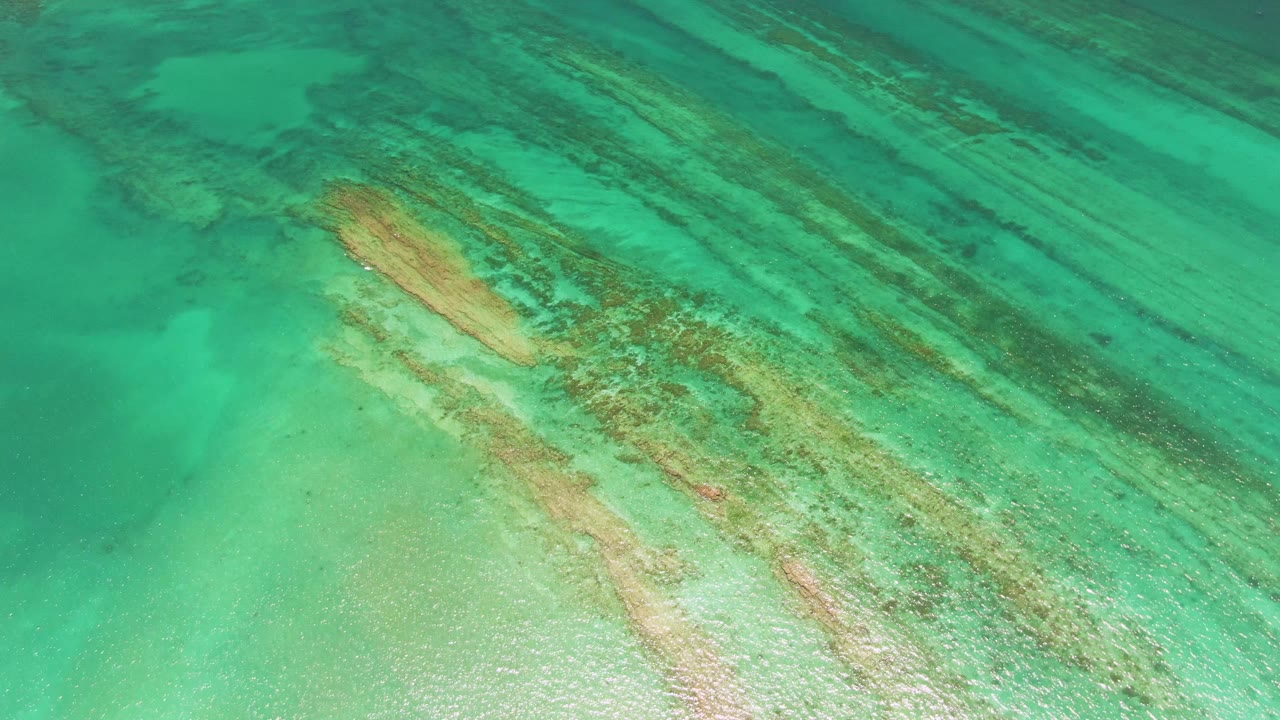 Clear green-blue water reveals a diagonal reef formation.