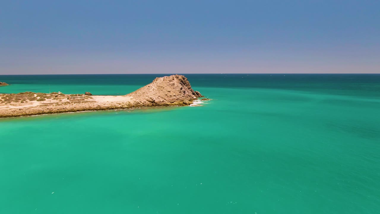 Rocky islet in turquoise ocean under a clear sky