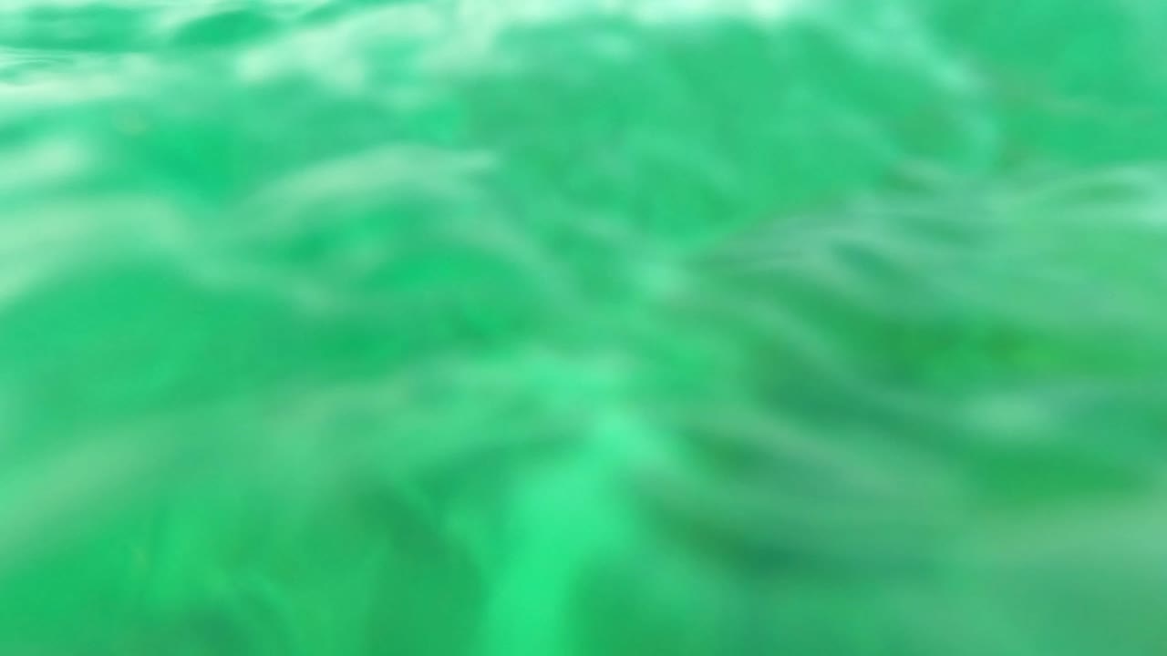 Blurred underwater moment in Los Barriles, Baja California Sur with rippled water near the surface and green water below, with no visible people.