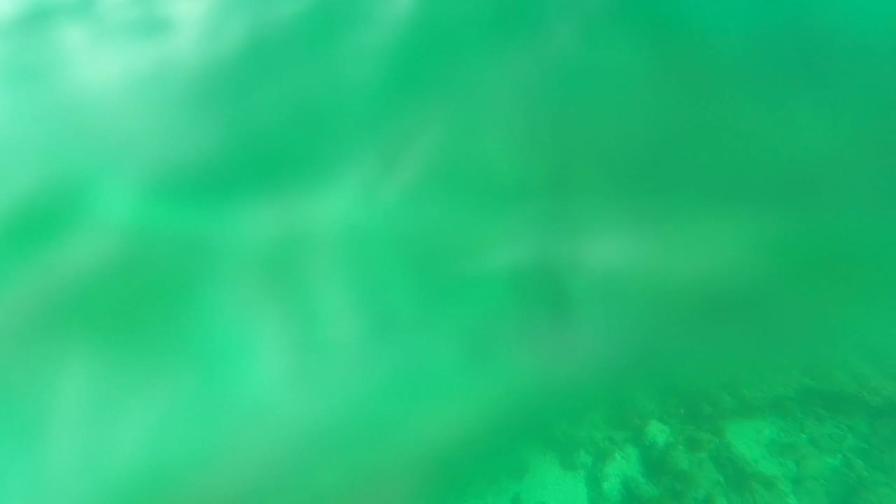 Soft, blurred turquoise underwater view over the rocky seabed at Los Barriles, Baja California Sur, with no visible people.