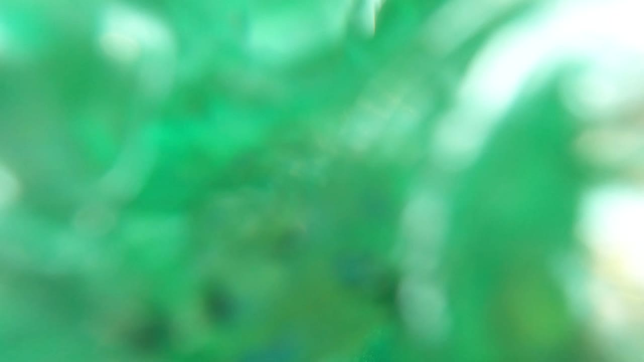 Soft, blurred underwater moment in Los Barriles, Baja California Sur, with green water, indistinct reef shapes, and no visible people.