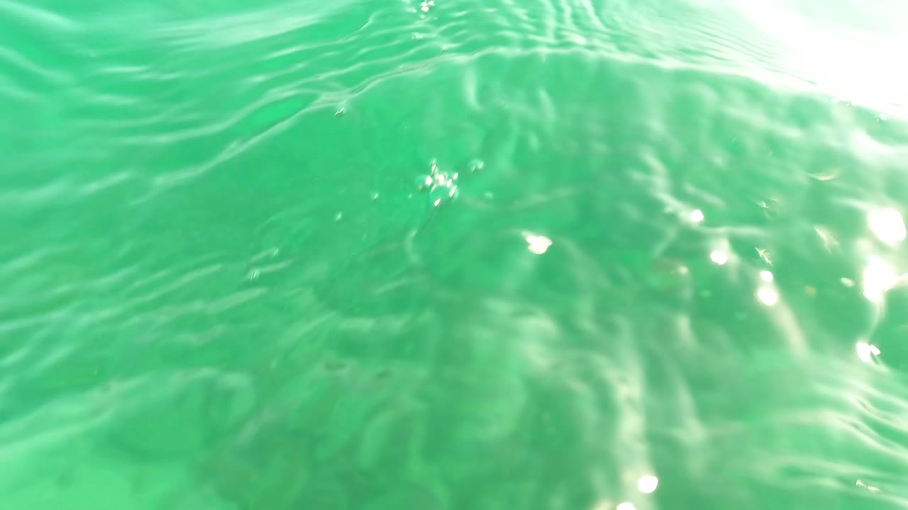 The camera is close to the water surface in Los Barriles BCS Mexico, with bright ripples above a green view of the seabed and no visible people.