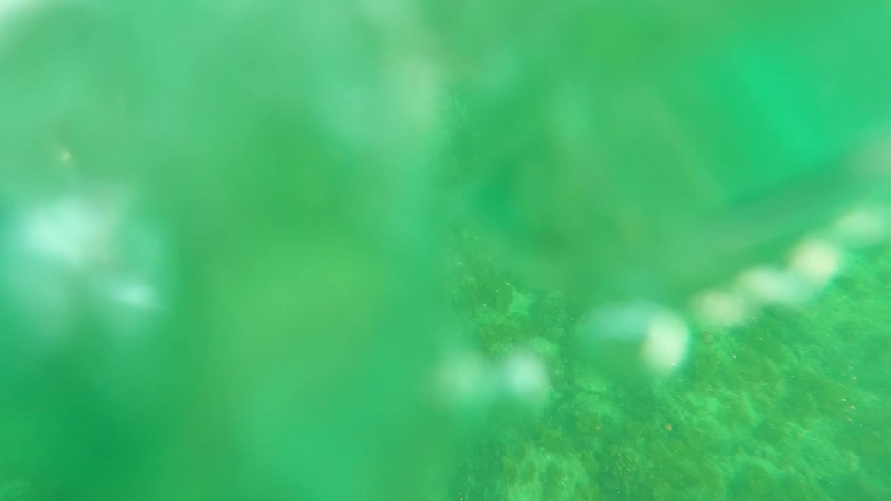Blurred green underwater frame near the water surface in Los Barriles, Baja California Sur, with soft highlights and no visible people.