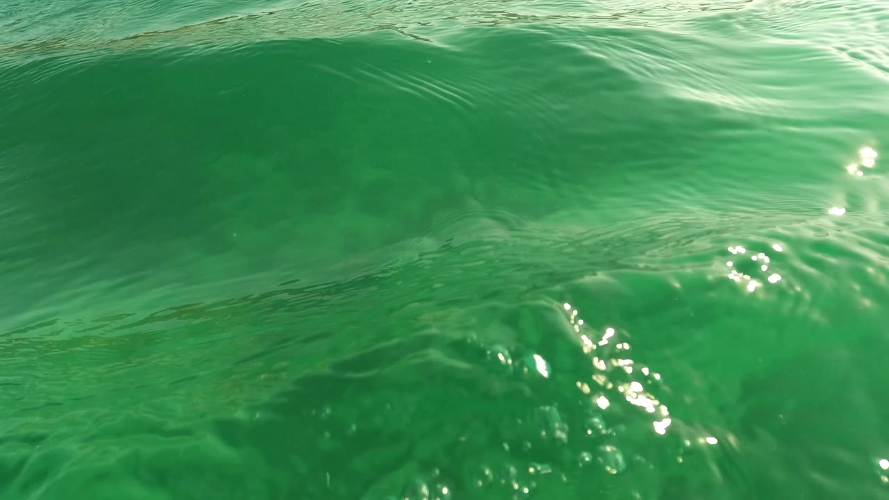 Green surface water with bright ripples and submerged bottom