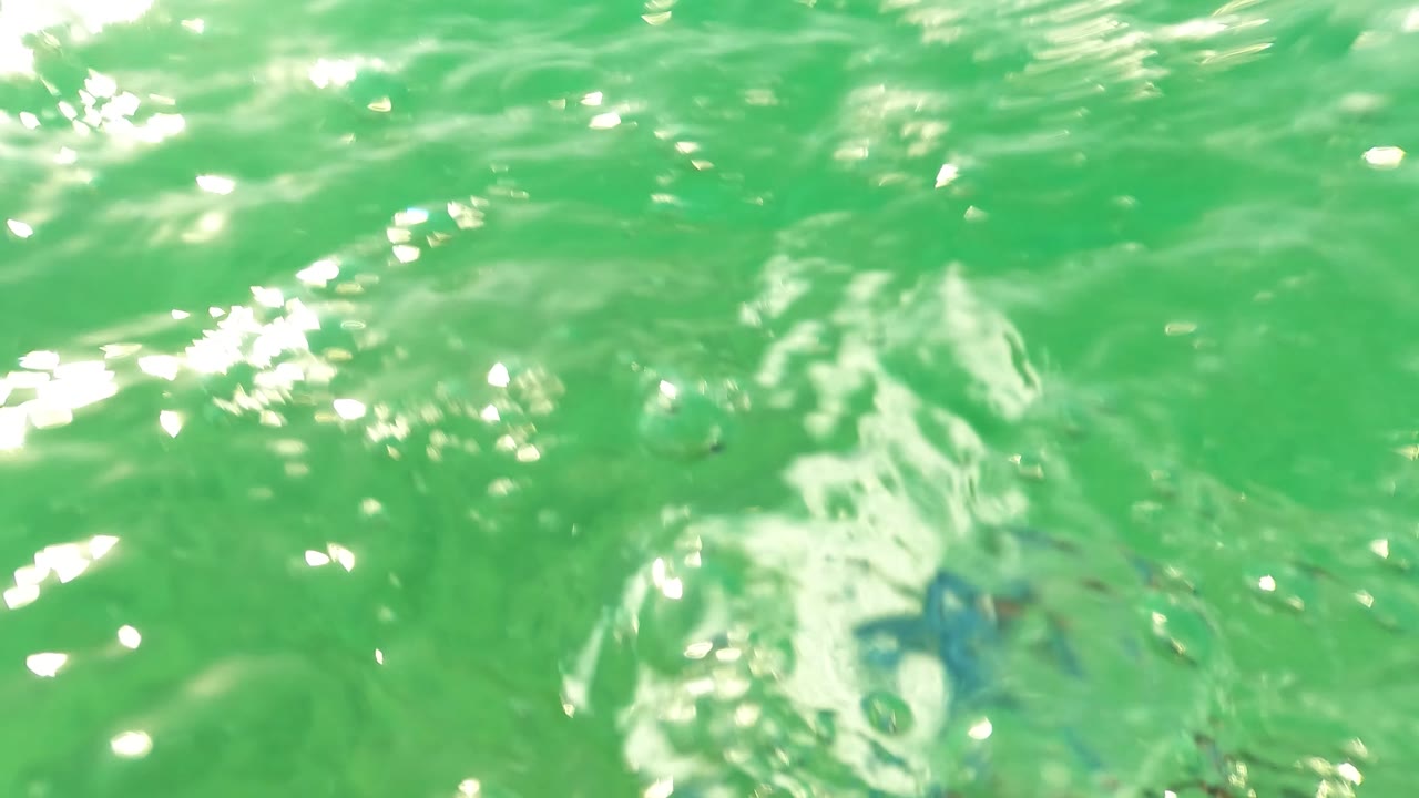 Bright surface-level water frame from Los Barriles with reflective ripples, green water, and no visible people.