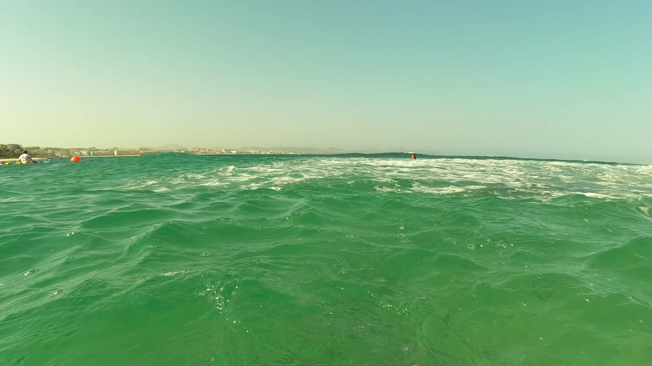 Water-level view of green ocean surface near Los Barriles, Baja California Sur, with low waves, a pale horizon, and no visible people.