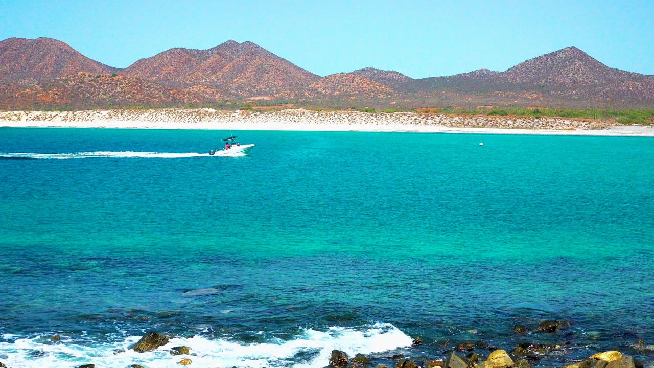 Small speedboat leaving a white wake across clear turquoise ocean.
