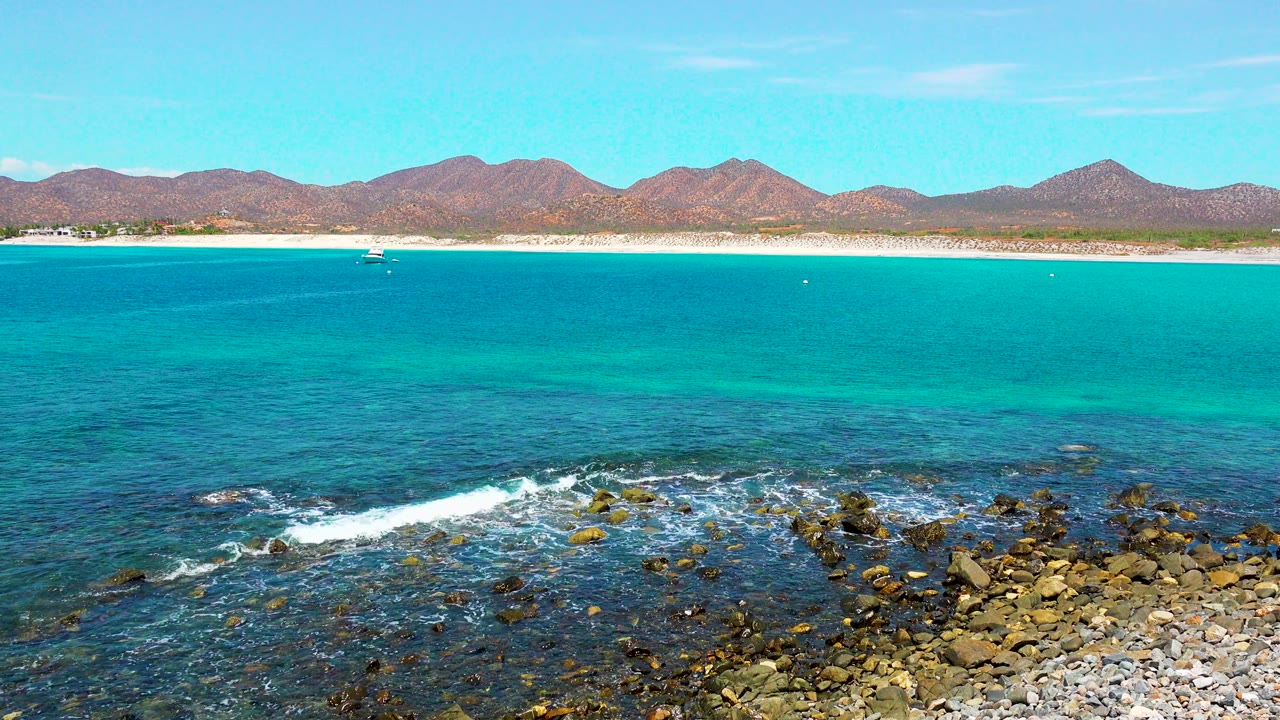 Small wave line approaching rocks in a turquoise coastal bay