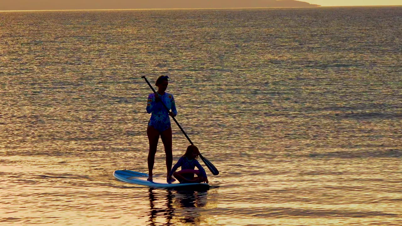 Woman paddling on a board as a child sits near the front